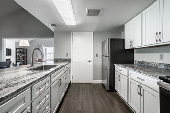 A modern kitchen with white cabinets and a black refrigerator.